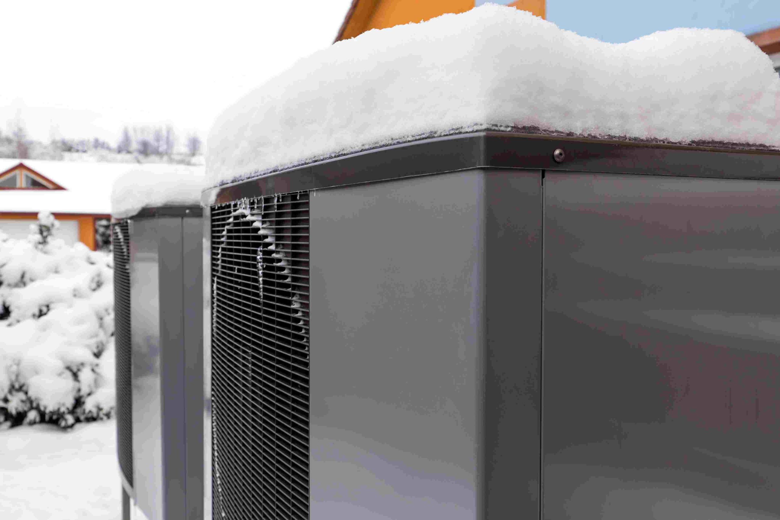 Two residential modern heat pumps buried in snow